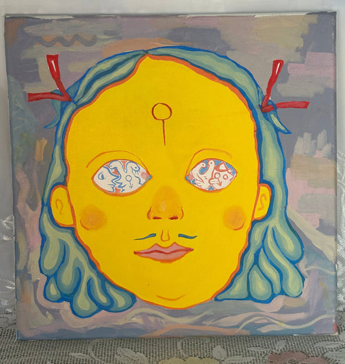 A square canvas painting featuring a stylized yellow face with blue hair and red ribbon accents, leaning against a light gray wall on a lace-covered surface.